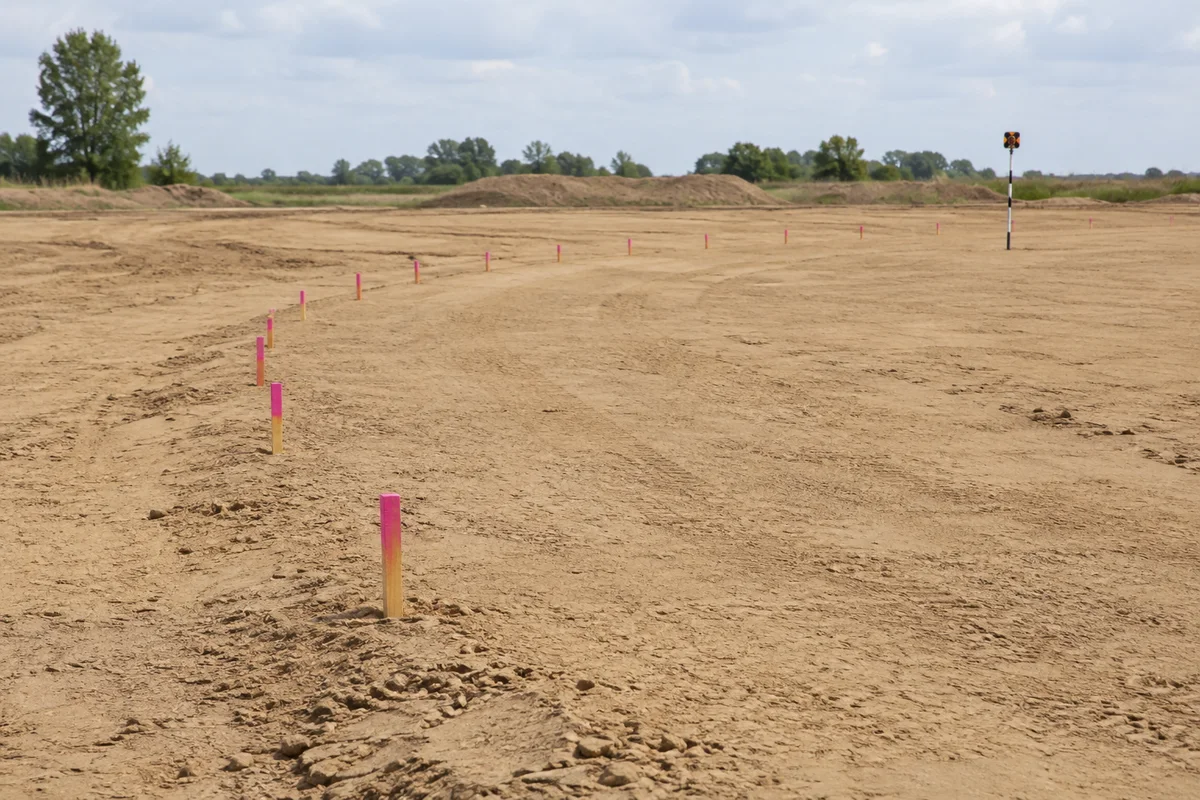 Survey pegs following an arc on compacted sand
